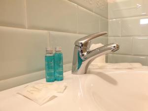 奥尔塔圣朱利奥阿拉柯利酒店的水槽,配有水龙头和2瓶玻璃瓶