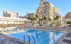 檀香山Ala Moana Hotel _ Ocean view with balcony的一座带椅子和建筑的大型游泳池