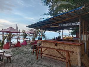 吉利特拉旺安fullesguesthouse的海滩上的酒吧配有桌子和遮阳伞