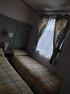 塔特舍尔hot tub luxury caravan 23 Lancaster tattershall lakes的一间卧室设有两张床和窗户。