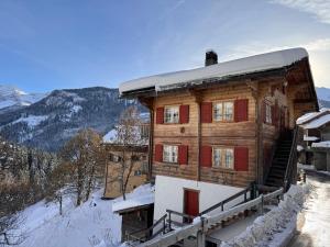 PeistBambi Lodge Ferienwohnung auf knapp 1400 m nahe Arosa的雪中带红色门的木屋