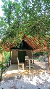瓦塔穆Bamba Kofi Tented Camp的树下带桌子和椅子的帐篷