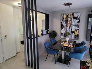 圣热尼普伊Appartement neuf moderne + parking, Genève的一间用餐室,配有黑桌和蓝色的椅子