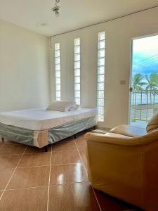 蒙加瓜Hostel Encanto de Mongaguá的一间卧室设有两张床、两把椅子和窗户。