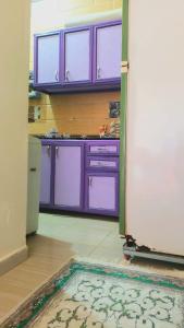 阿布辛贝Mooody nobin haws的厨房配有紫色橱柜和地板上的地毯
