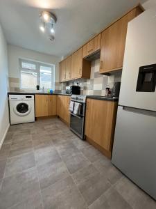 南安普敦St Denys 2 bedroom flat, Convenient location next to station, Great for contractors的厨房配有木制橱柜和白色冰箱。