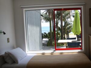 库珀海滩Driftwood Beachfront Accommodation, Cable Bay, Owhetu的一间卧室设有窗户,享有海滩美景