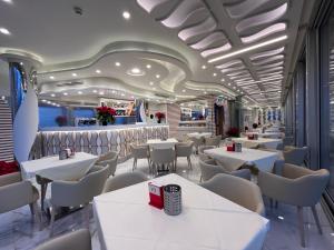 阿尔盖罗玛格丽特SPA酒店的一间设有白色桌子和白色椅子的餐厅