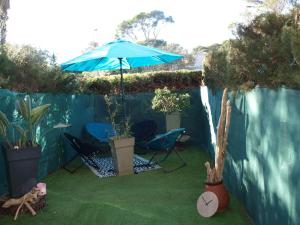 圣拉斐尔Studio le Mistral的庭院配有两把椅子和蓝伞