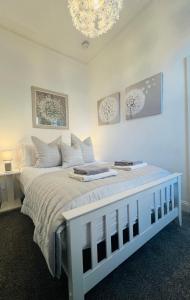 斯特灵Cosy Cottage的白色卧室配有白色的床和吊灯