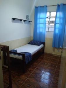 蒙加瓜pousada&Hostel perola mar的一间小卧室,配有一张带蓝色窗帘的床