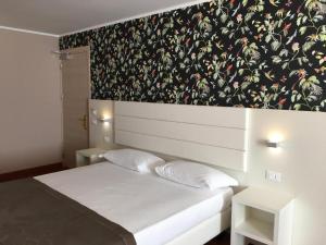 罗索利纳Hotel Formula Int. & Puravita SPA的卧室配有白色床和花卉壁纸