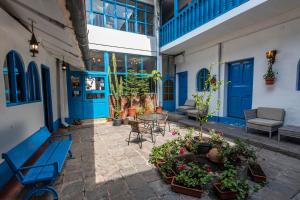 库斯科La Casona de Rimacpampa的一个带蓝色门和桌椅的庭院