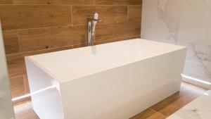 莫斯塔尔HA Hotel Mostar的浴室设有白色浴缸,拥有木墙