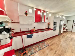 特尔德Black Sand Loft的一间大厨房,配有白色的橱柜和红色的点缀