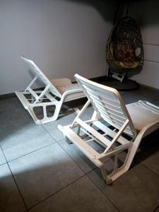 科拉雷侯Fuerte Vibes Guest House In Corralejo的两把白色躺椅(位于瓷砖地板上)