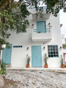 多拉代尔Cabaña Villa Jardín - Aldea Doradal - Santorini Colombiano的白色的房子,有蓝色的门和盆栽植物
