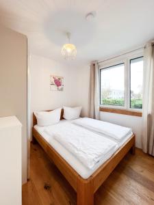 维也纳Modern apartment w/ cozy balcony near city center的一间卧室配有一张带白色床单的床和一扇窗户。
