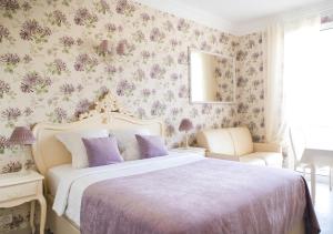 戛纳Croisette Palais Miramar Cannes Imperial的一间卧室配有一张带紫色枕头的大床