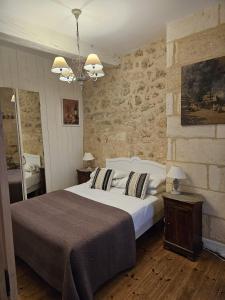 圣艾米隆柯林尼旅馆的一间卧室设有一张大床和石墙