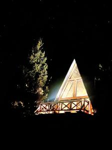 ČajničeHanina Village Resort - l i ll的金字塔形的建筑,晚上有木桥