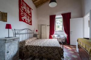 菲纳莱利古雷Agriturismo La Contessa的一间卧室配有床和红色窗帘的窗户