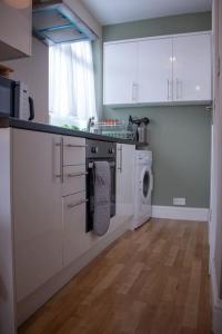 伦敦Cosy apartment 7 mins walk from Wembley stadium的厨房配有白色橱柜和洗衣机。