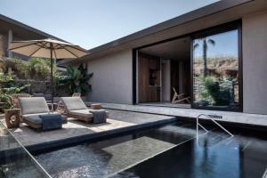 加藤-达拉特索Domes Zeen Chania, a Luxury Collection Resort, Crete的一座带游泳池、两把椅子和一把遮阳伞的房子