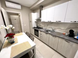 圣欧费米亚拉默齐亚B&B VIRGILIO LAMEZIA AIRPORT的厨房配有白色橱柜、桌子和水槽。