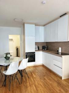 维也纳Danube22 Apartment 2的厨房配有白色橱柜和桌椅