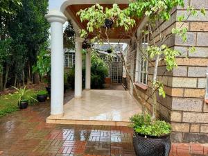 内罗毕Charming Retreat in Garden Estate-Thome, Thika Rd的柱子和植物的房屋门廊