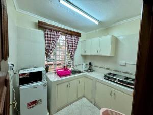内罗毕Charming Retreat in Garden Estate-Thome, Thika Rd的厨房配有白色橱柜、炉灶和窗户。