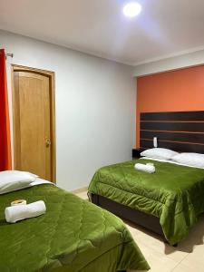 瓦拉斯Hotel Los Pajonales的一间卧室设有两张带绿床单和橙色墙壁的床。