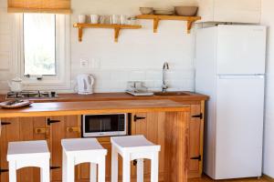 德尔迪阿布罗角Cabaña Agua de Mar的厨房配有白色冰箱和白色凳子