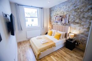 伦敦Luxury Fulham 3 bedroom Garden House的一间卧室配有一张带黄色枕头的床和一扇窗户