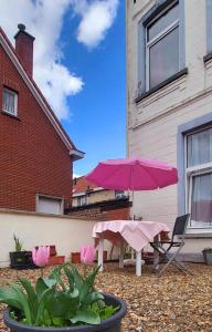 布鲁塞尔Handy Studio near Nato的一个带粉红色遮阳伞和桌椅的庭院