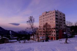 ShimotakaiT Hotel Ryuoo的滑雪者在建筑物前的雪中