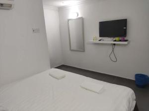 瓜埠Vive Inn的白色的客房设有一张床和墙上的电视