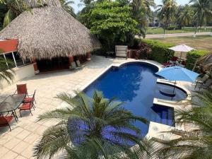 圣何塞港Casa Gaviota的一个带茅草屋顶的大型游泳池的度假酒店