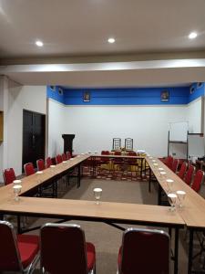 巴东Surya Palace Syariah的一间会议室,配有长桌子和红色椅子