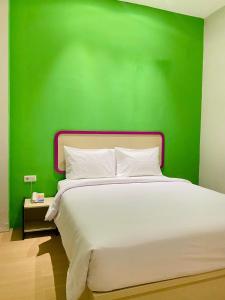 SukaramiRuma Ruma Hotel Kenten - Palembang的一间卧室设有绿色的墙壁和一张白色的床
