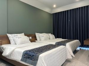 Plei BrêngRiWin Hotel Pleiku的配有白色床单的酒店客房内的两张床