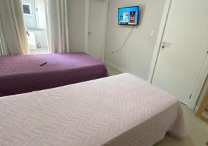 伊达贾伊Suíte Premium的一间卧室设有两张床,墙上配有电视。