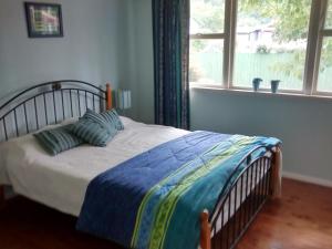 TuamarinaSunrise Beach House - Rarangi Holiday House的卧室配有一张带两个枕头的床和窗户