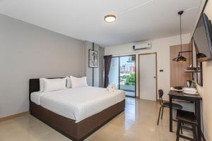 曼谷CK2 Hotel SHA EXTRA PLUS的卧室配有白色的床、书桌和窗户。
