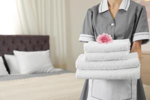 珀斯珀斯皇冠假日酒店的一位女士在旅馆房间拿着一堆毛巾