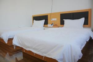 梅州湄洲岛悦榕湾民宿的配有白色床单的酒店客房内的两张床