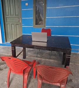 占碑市SPOT ON 93465 Archa Guest House Syariah的一张桌子,上面有两把红色椅子和一台笔记本电脑