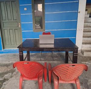 占碑市SPOT ON 93465 Archa Guest House Syariah的一张桌子,上面有两把红色椅子和一台笔记本电脑