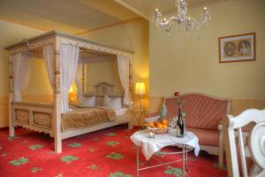 永斯多夫Romantik Hotel Zum Lindengarten的一间卧室配有一张天蓬床和一张桌子